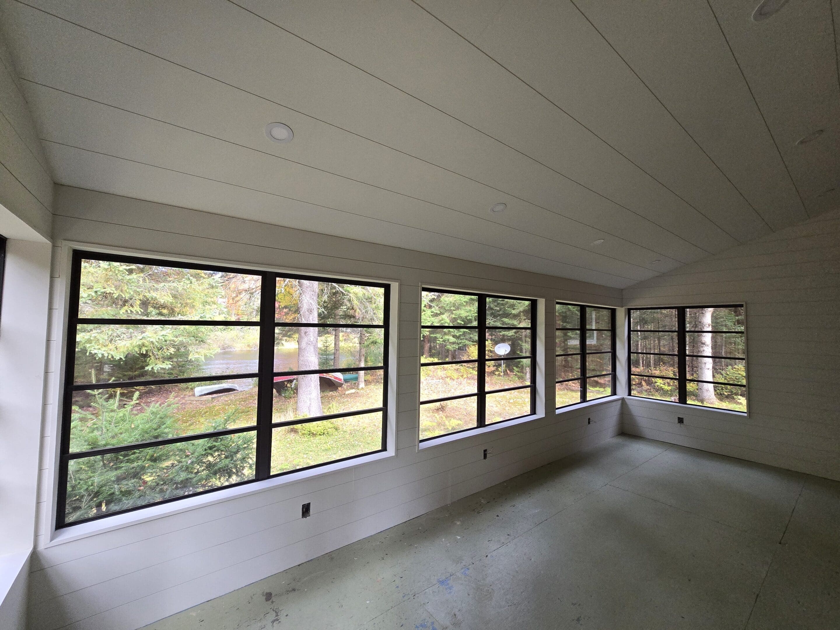 Empty sunroom with large black-framed windows