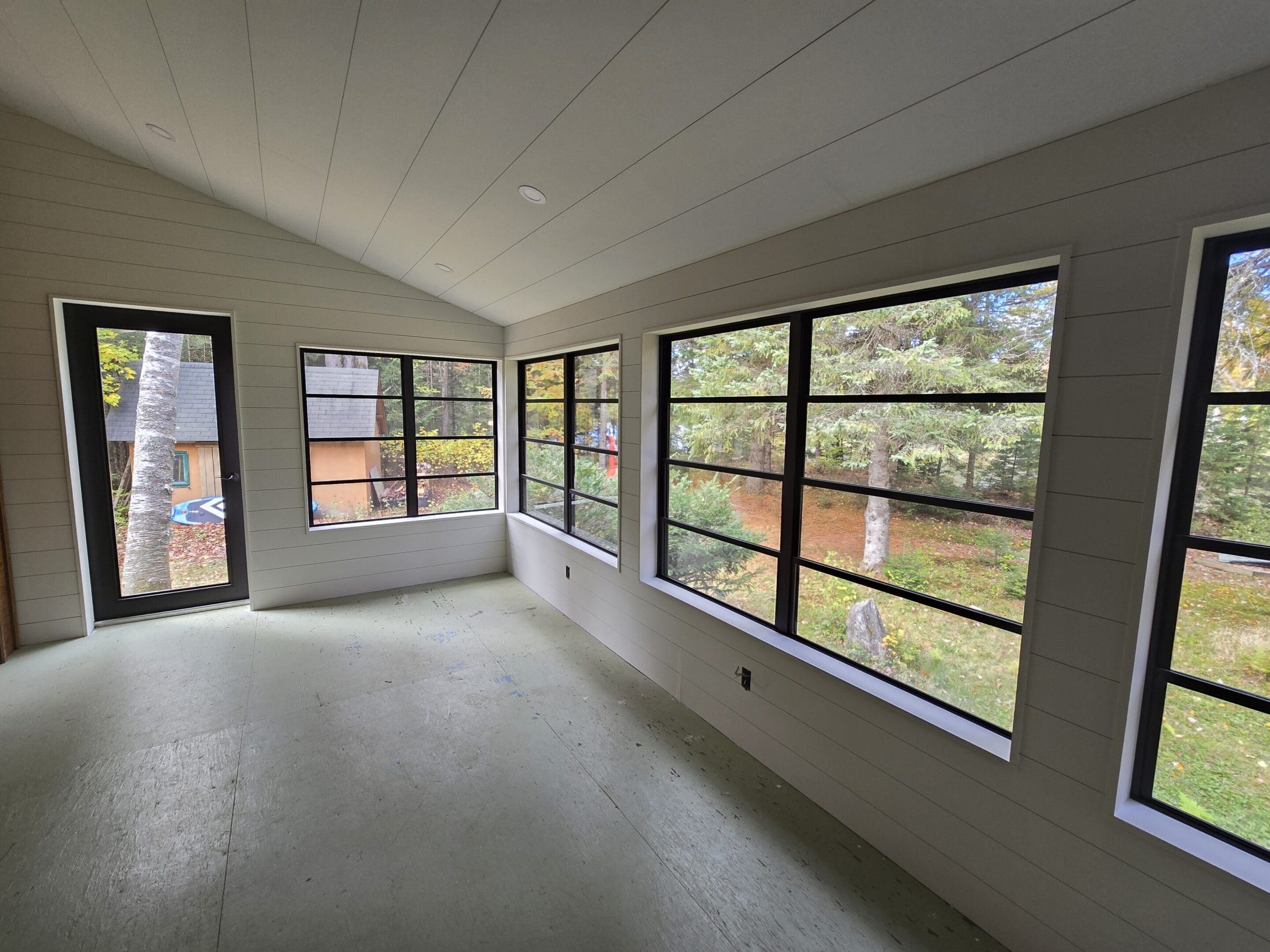 Empty sunroom with large black-framed windows